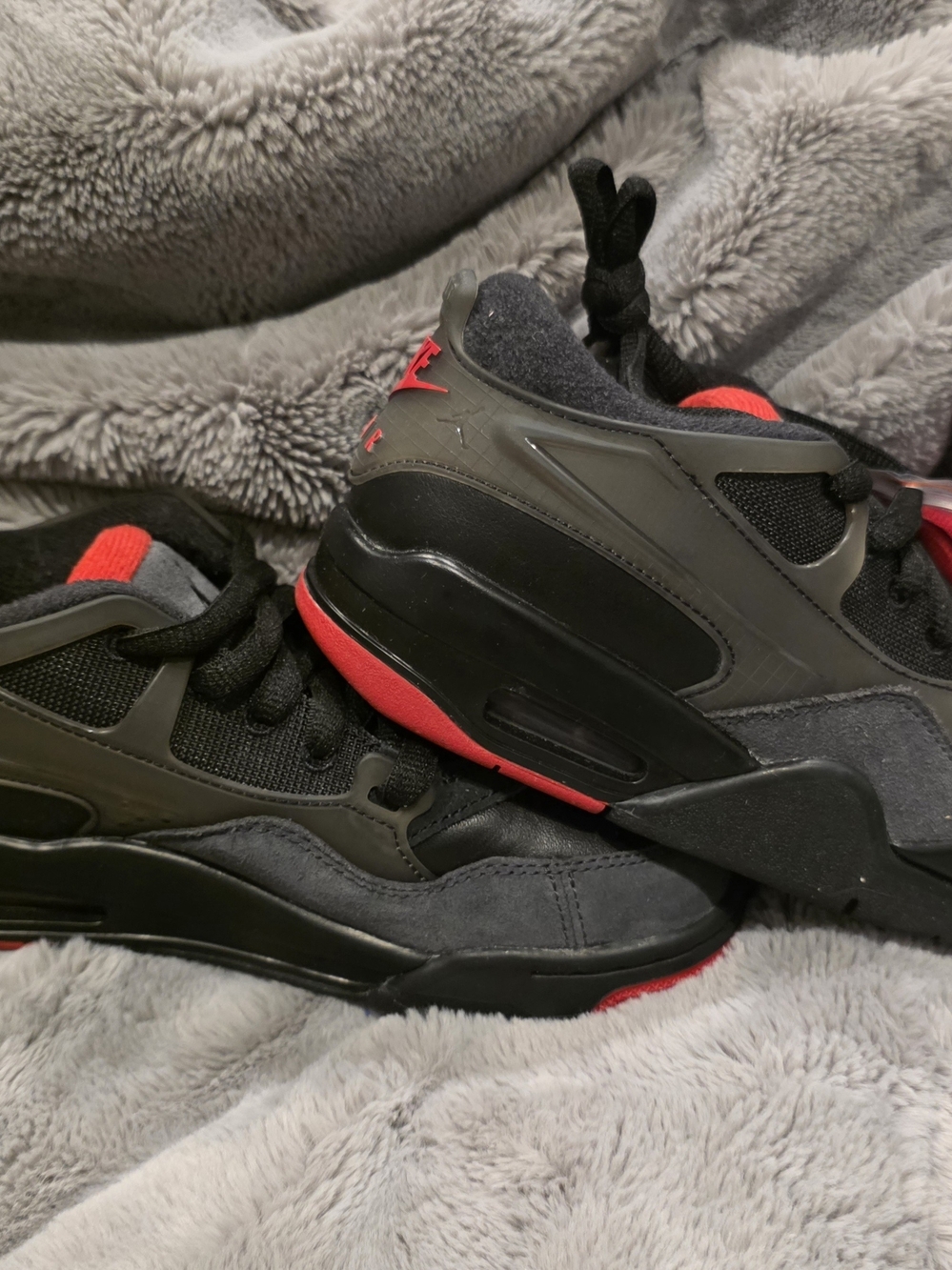 Nike Jordan 4 RM sneakers featuring a black upper with varsity red accents.